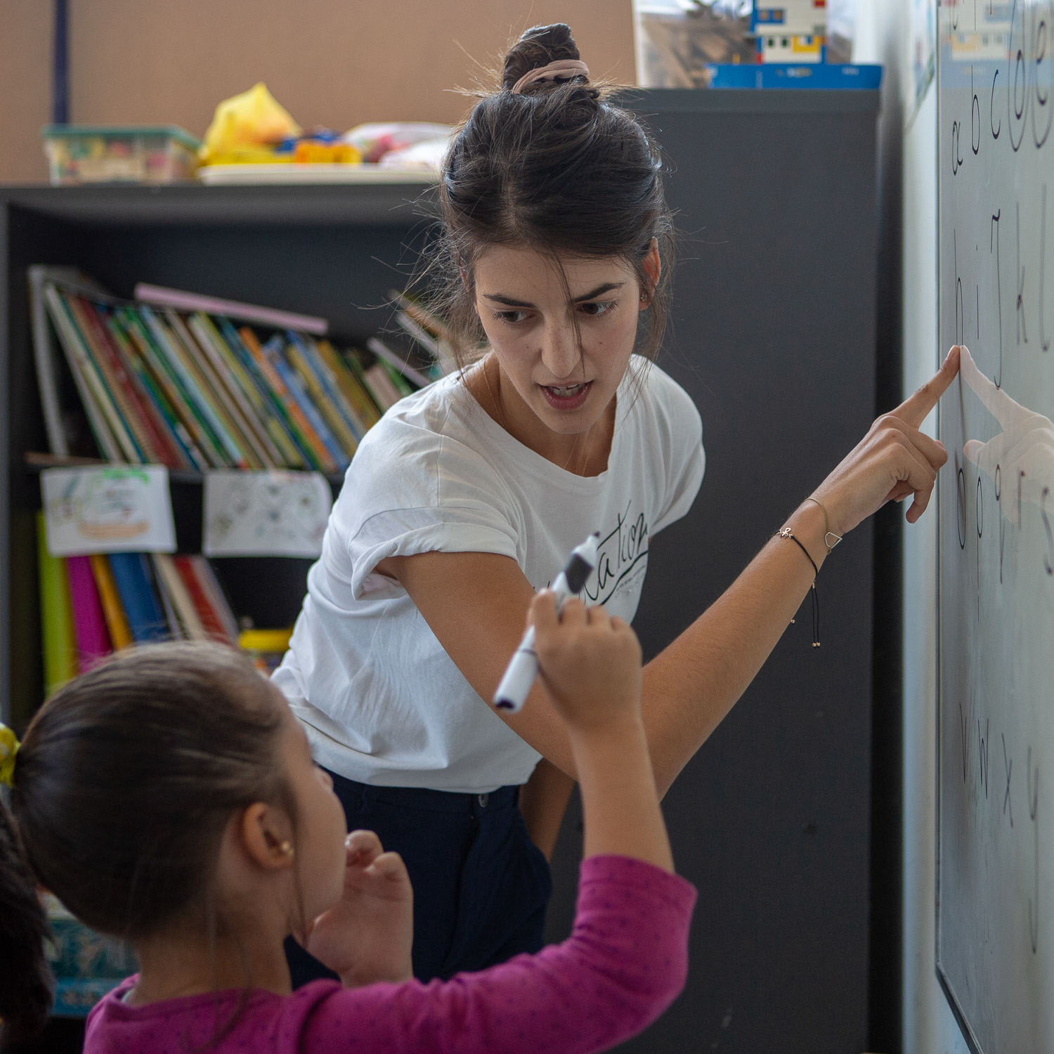 A teacher explains the greek alphabet on a whiteboard
