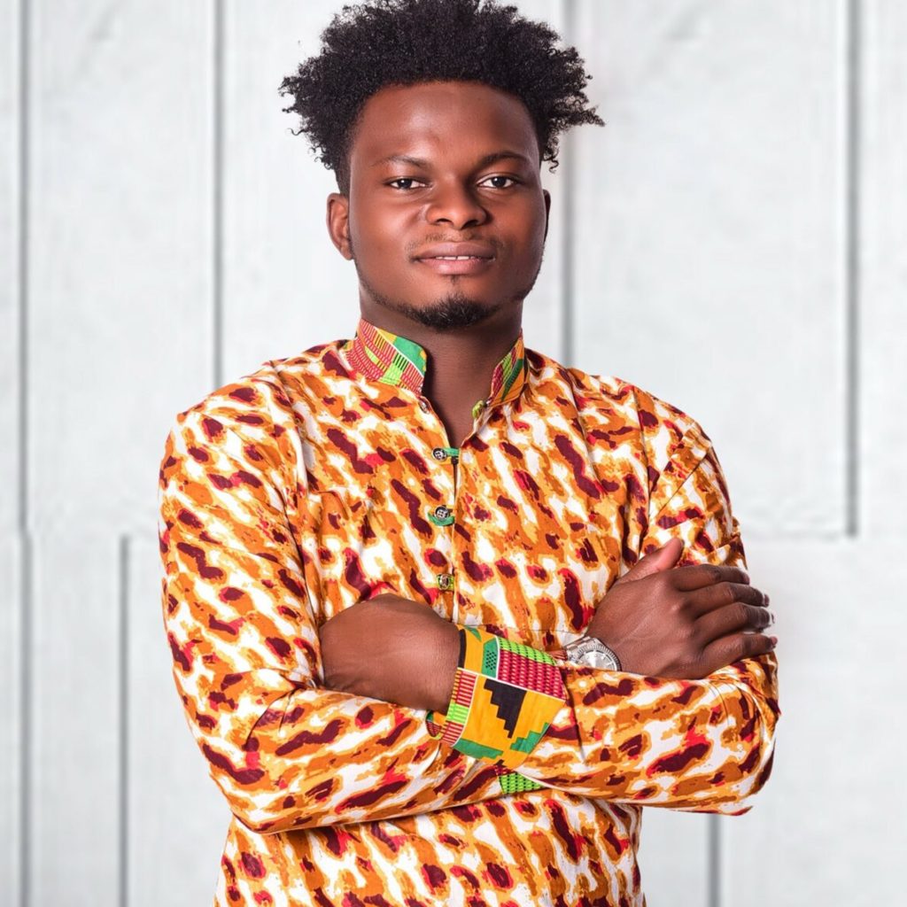 A portrait of Jeremiah Thoronka smiling with his arms crossed and wearing a colorful orange, red, and green patterned tunic